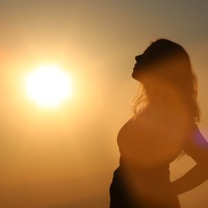 Woman looking off into the distance with a setting sun behind her